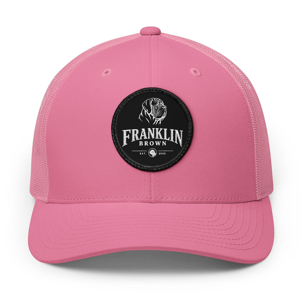 Pink trucker cap with mesh back and black circular patch featuring a dog logo and 'Franklin Brown' text, adjustable snapback closure