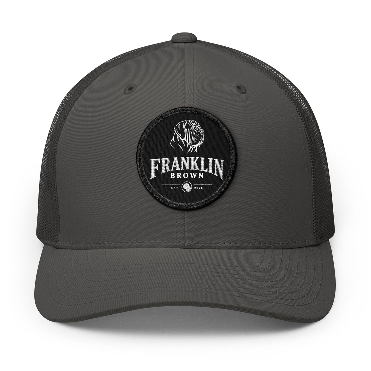 Black trucker cap with mesh back and black circular patch featuring a dog logo and 'Franklin Brown' text, adjustable snapback closure