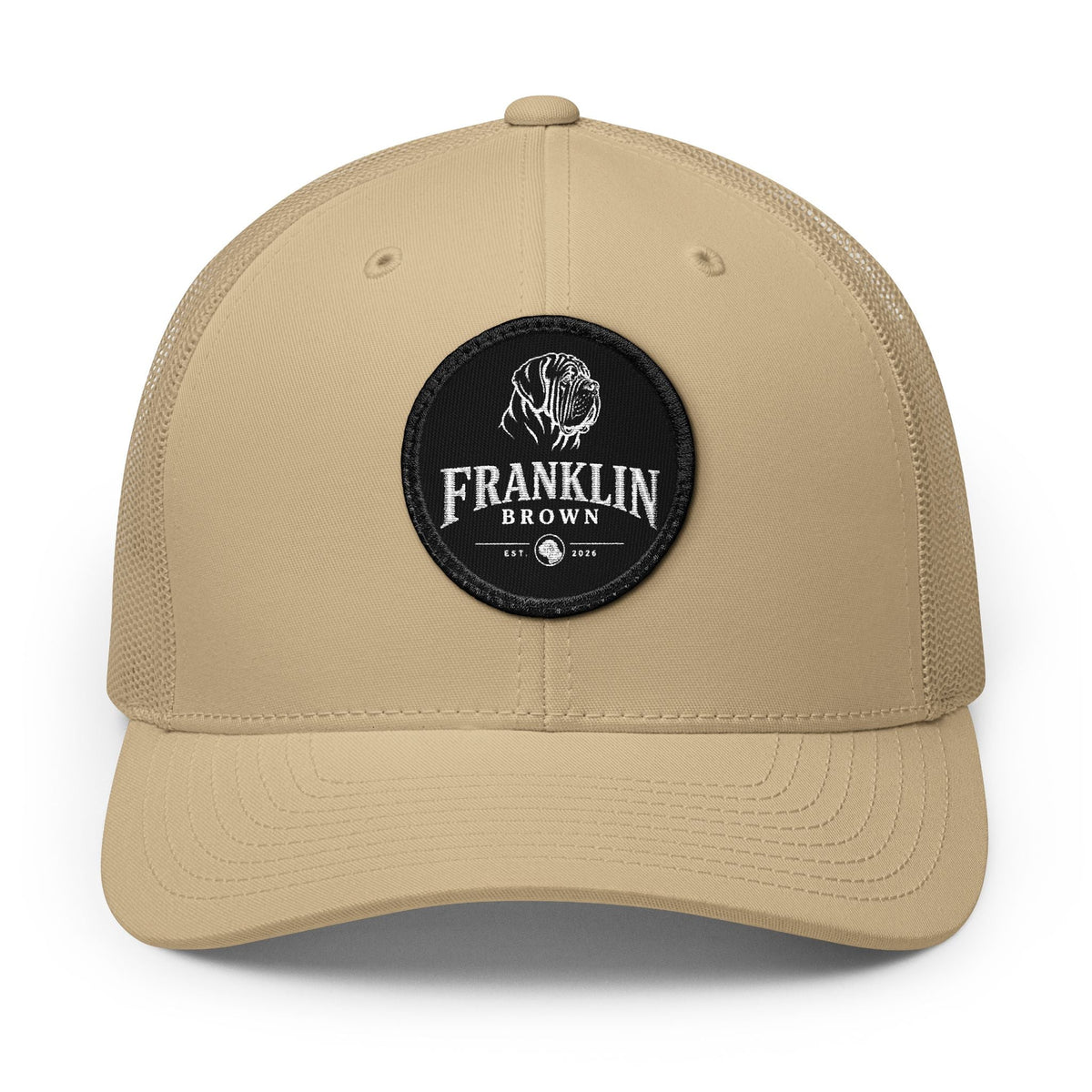 Beige mesh trucker cap with a round top button and adjustable snapback closure, featuring a black circular patch with a dog logo and 'Franklin Brown' text